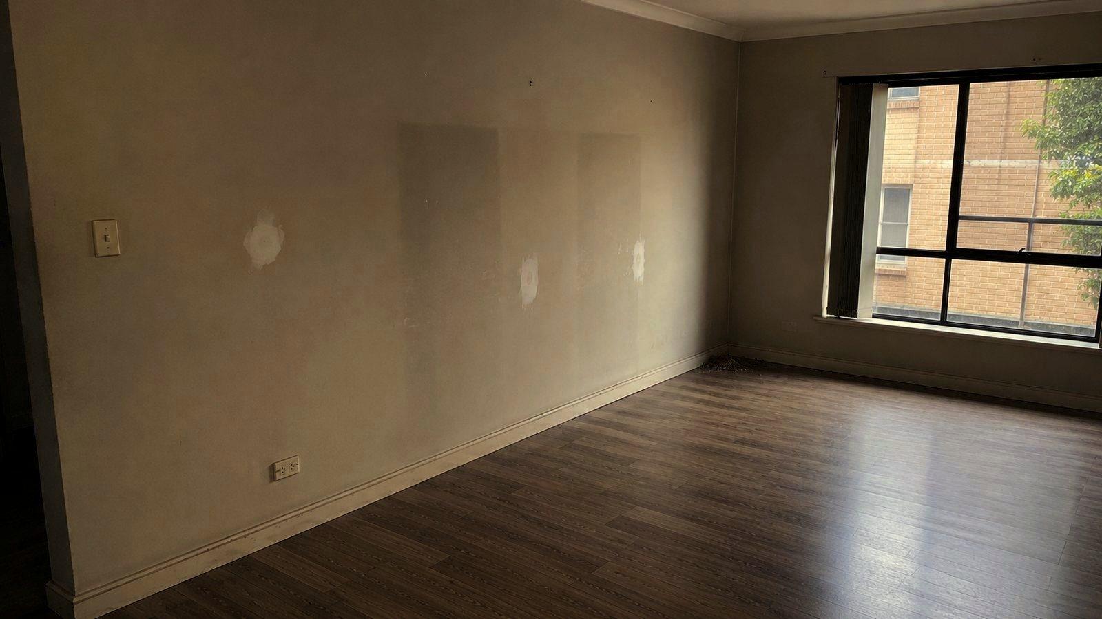 An empty rental living room with filled and sanded wall patches ready for the final inspection