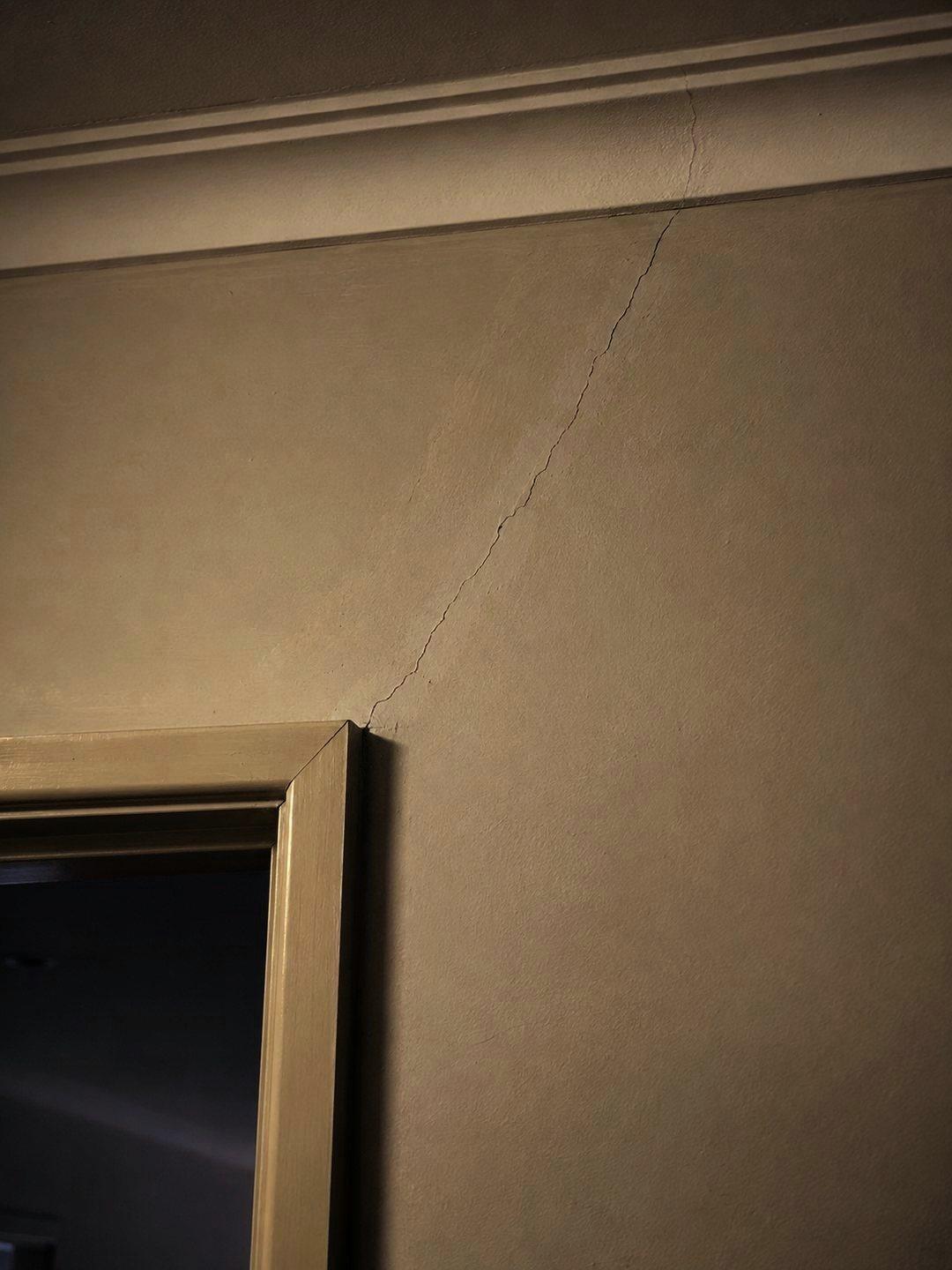 A hairline crack running diagonally from a door frame corner up to the cornice