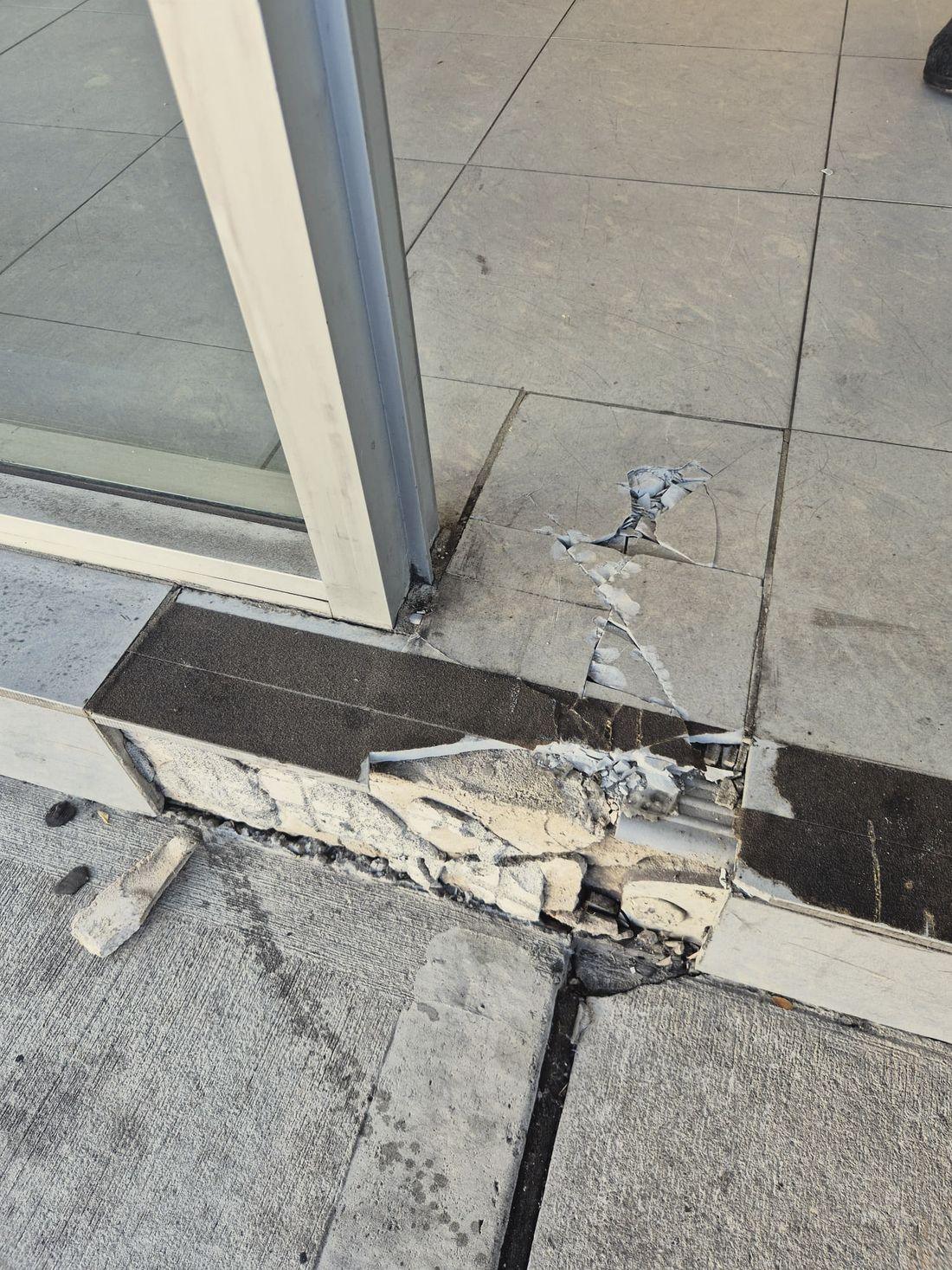 A shopfront sliding door threshold with the concrete blown apart and chunks lifted out