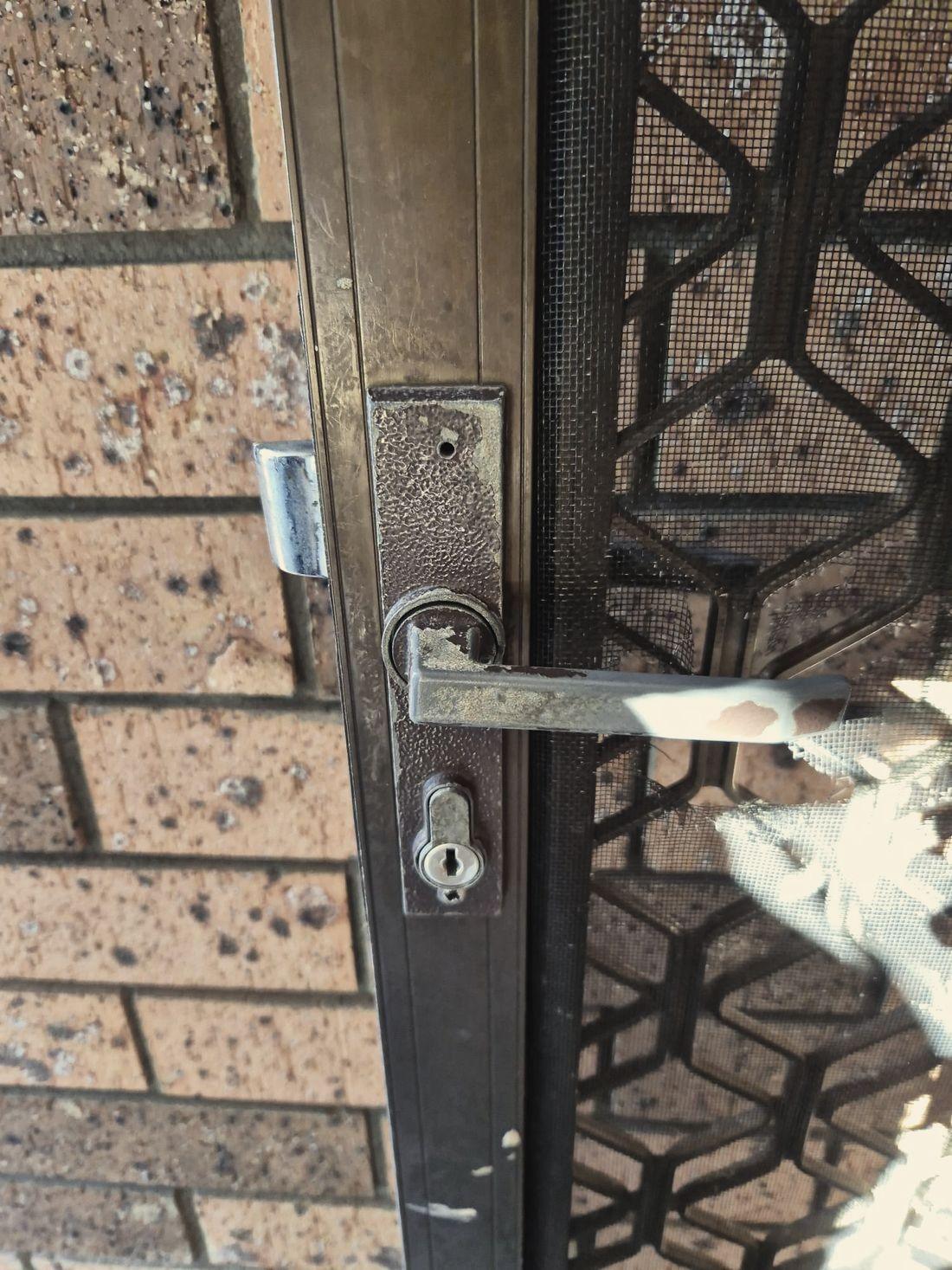 A security screen door handle and lock with the paint worn through