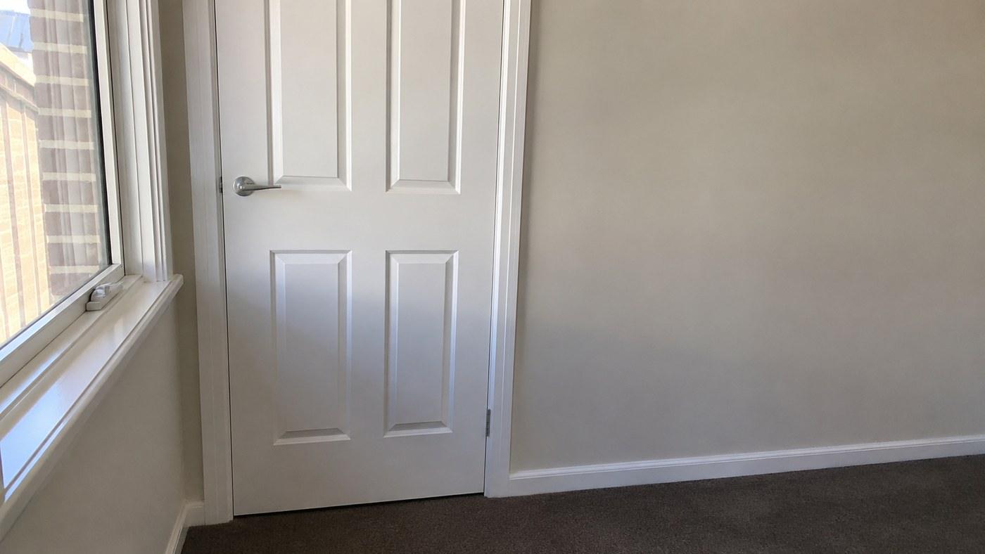 An interior door and its trim cut in by hand against a finished wall