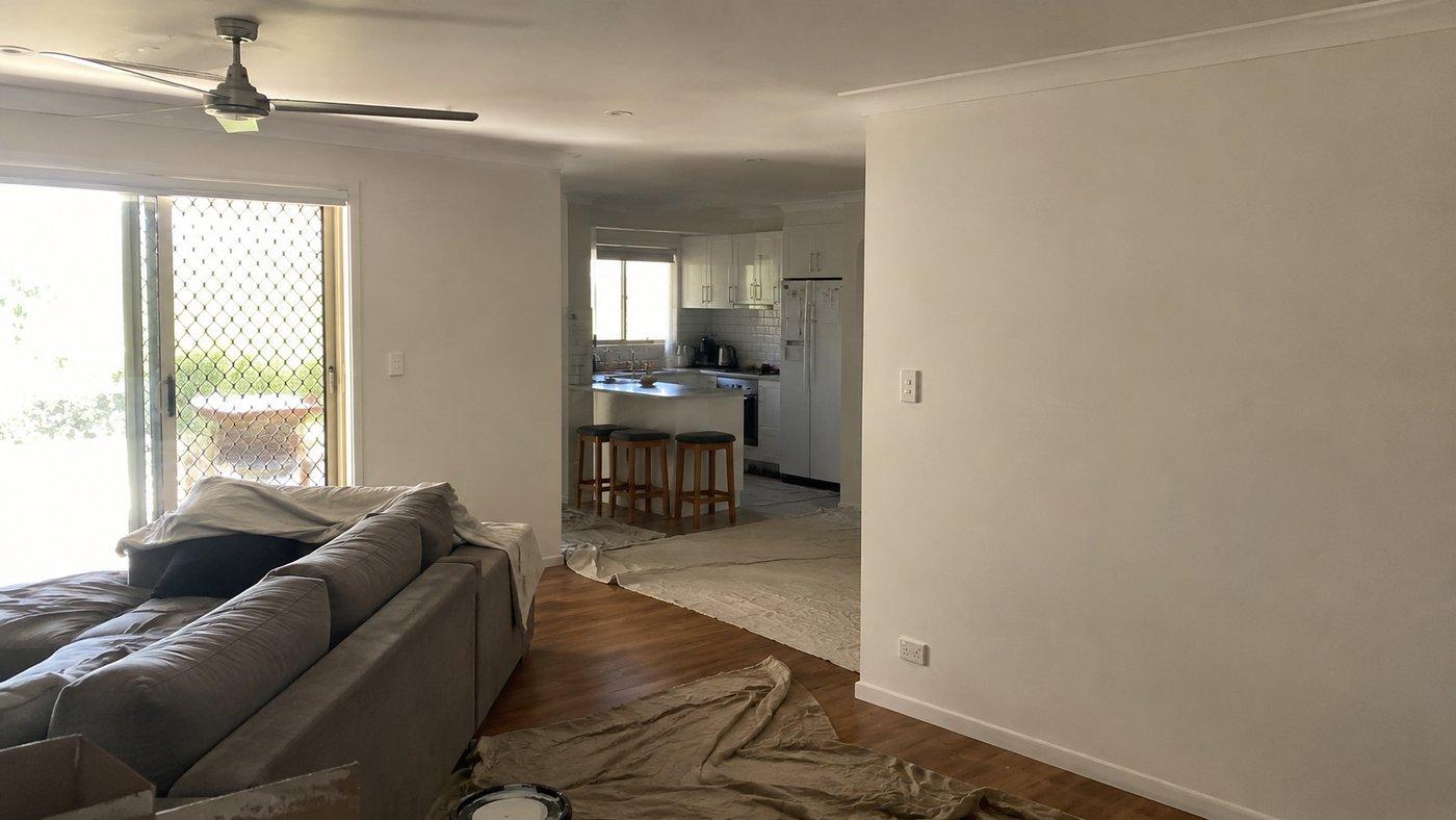 A living room repainted, drop sheets still down along the skirting