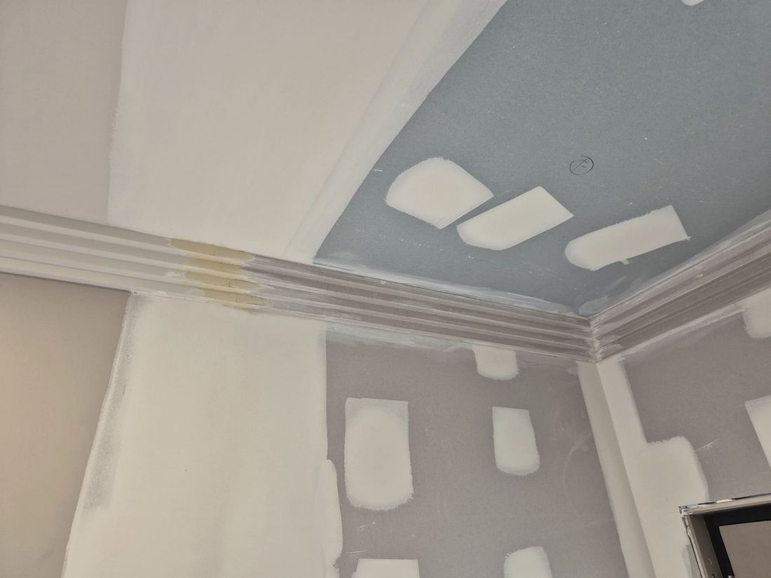 A cornice corner cut and set, masking tape still on, part way through the job