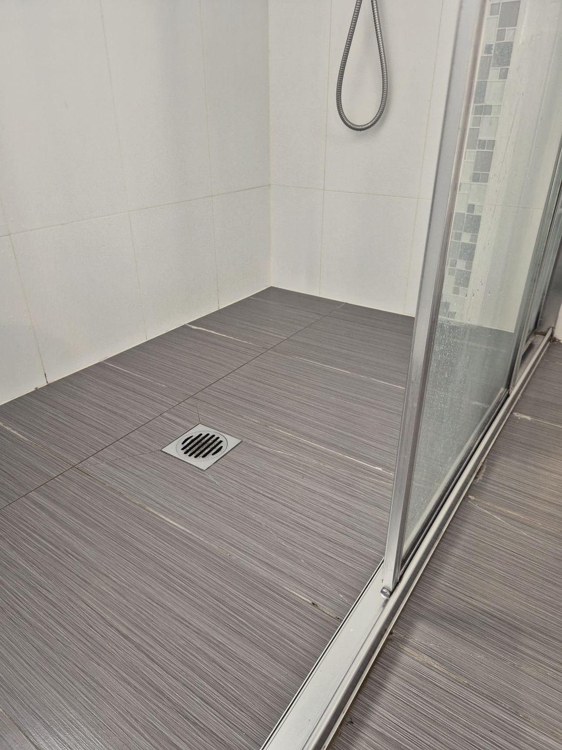 Inside a shower recess, the floor falling to the waste with the screen in place