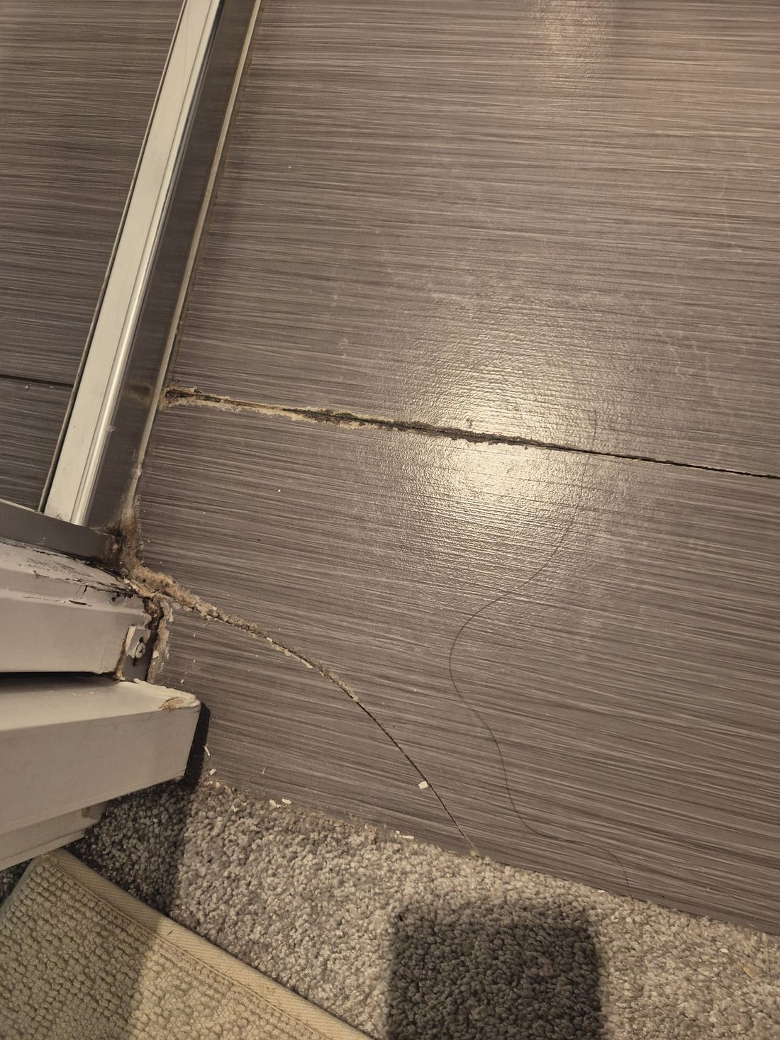 A blown out grout line and a chewed up door jamb at a bathroom threshold