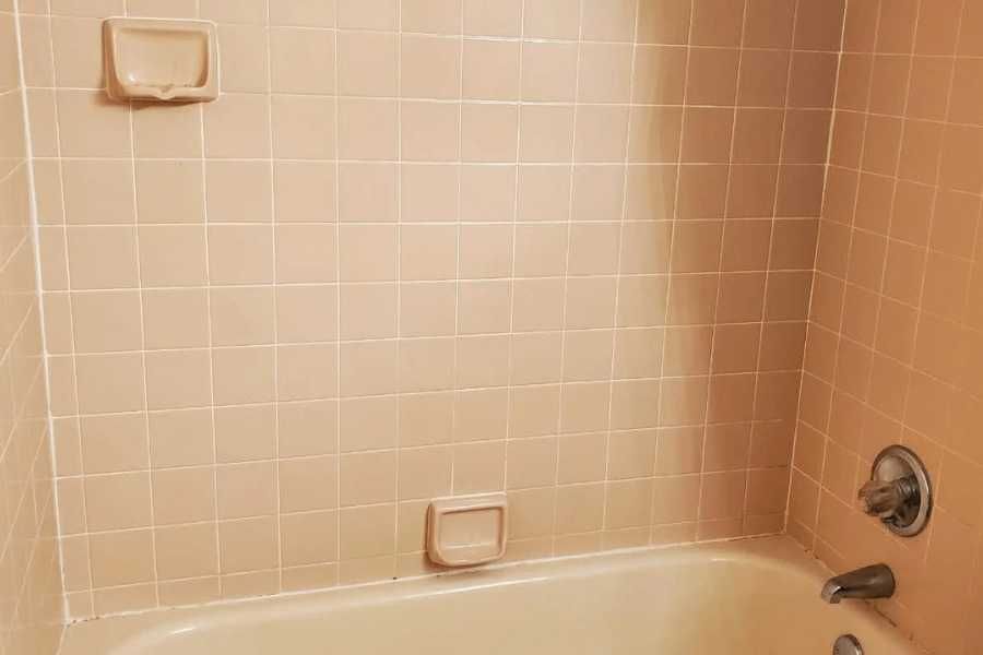 An apricot tiled bathroom wall and bath, dated and discoloured